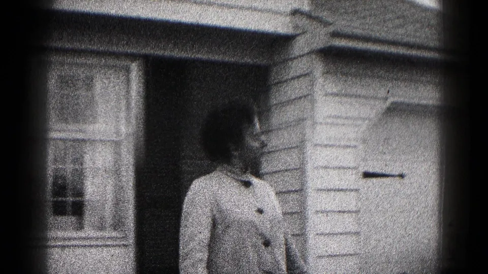 The closing frame shows the woman outside the residence, with a window and garage door in view.