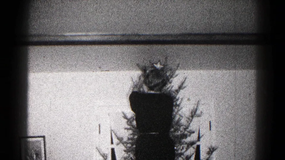 The 1959 Hagerstown home-movie frame shows the Christmas tree, star topper, wall picture, and holiday decorations in soft focus.