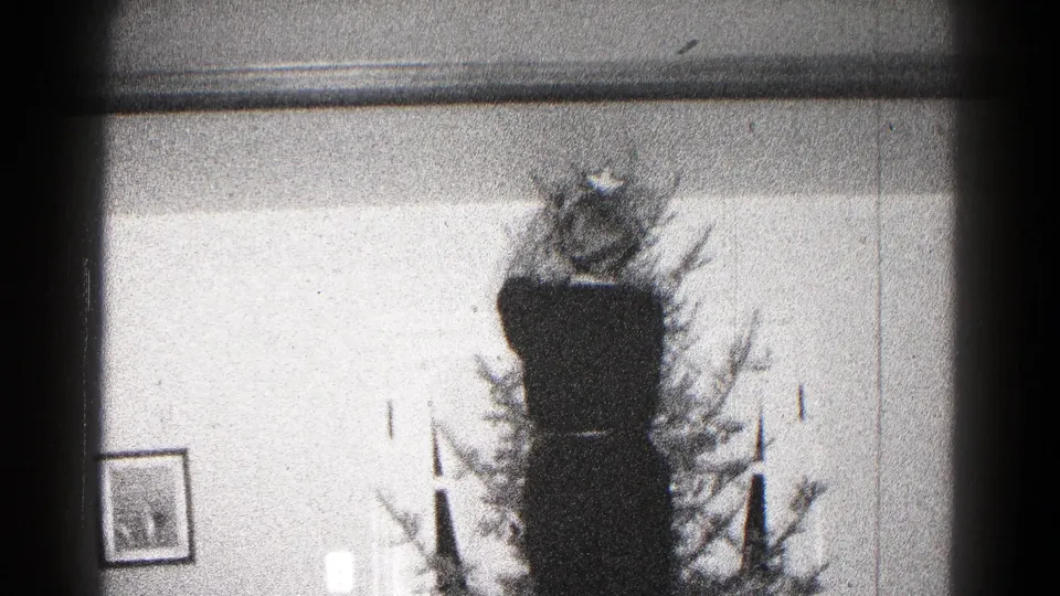 A grainy 1959 Hagerstown frame holds on the star-topped Christmas tree with wall molding and small decorations nearby.