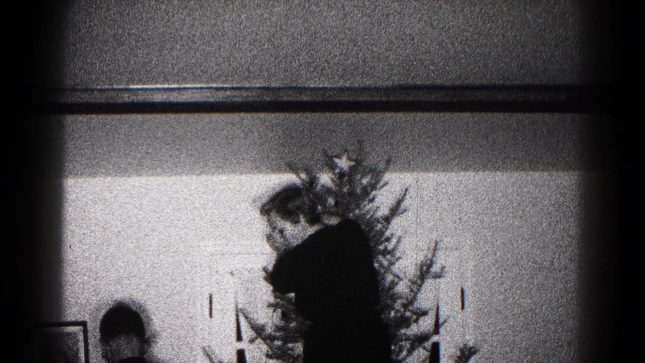 Silhouetted adult and child near a Christmas tree inside a home.