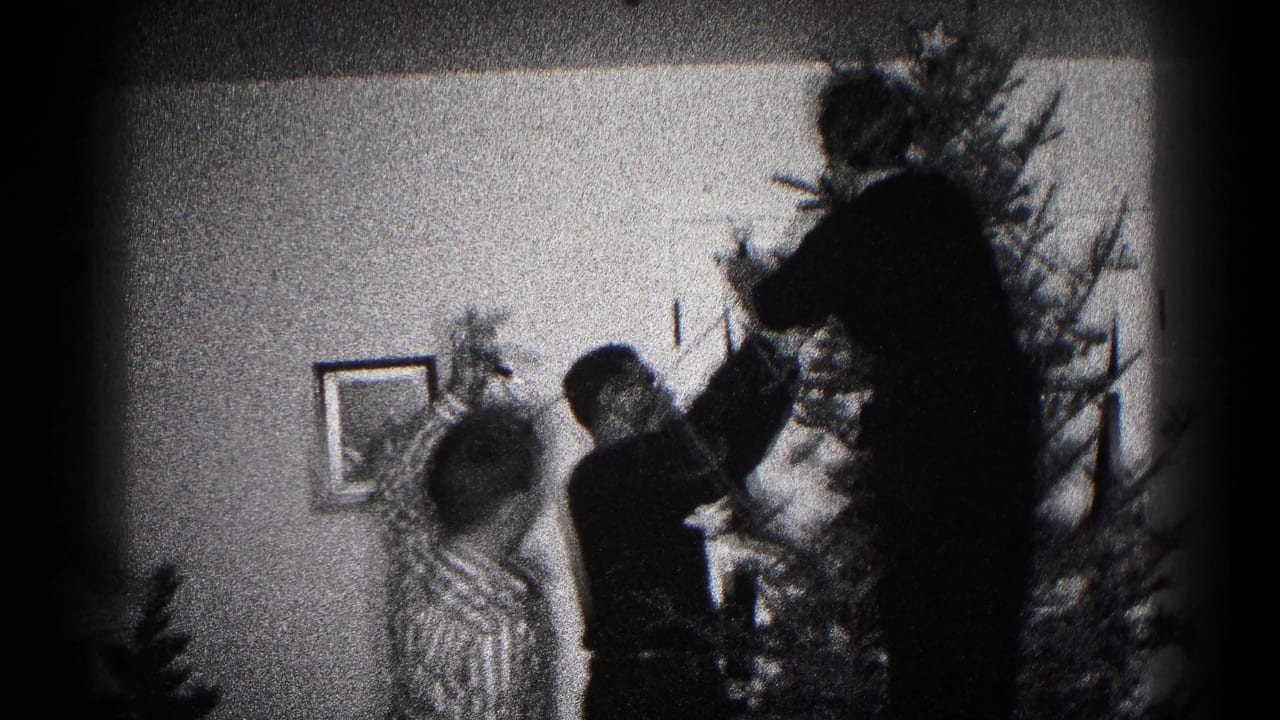 Family members in a 1959 Hagerstown interior appear to place decorations on a Christmas tree, seen in grainy black-and-white 8mm footage.