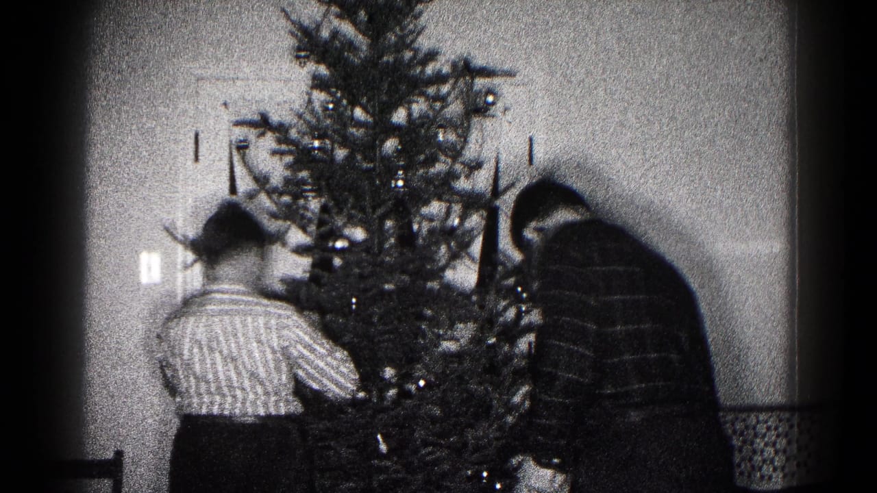 Late frame of the 1959 home-movie clip with family members continuing to decorate the indoor Christmas tree.
