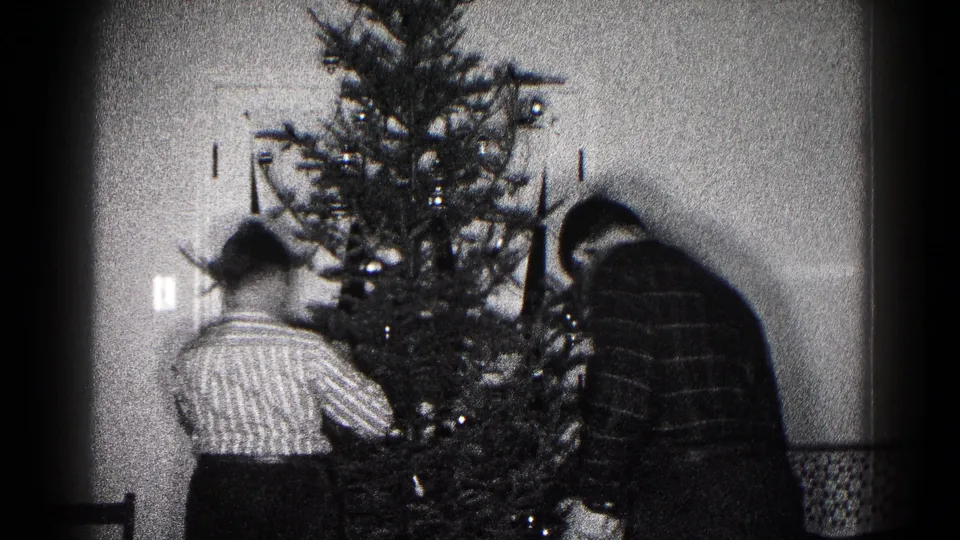 Late frame of the 1959 home-movie clip with family members continuing to decorate the indoor Christmas tree.