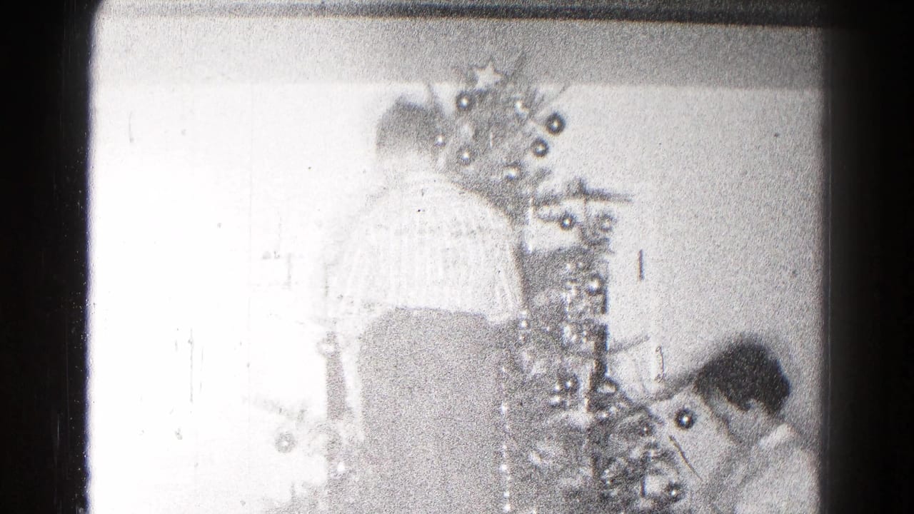 Bright home-movie frame of a decorated Christmas tree and a person near the base inside a private 1959 Hagerstown home.