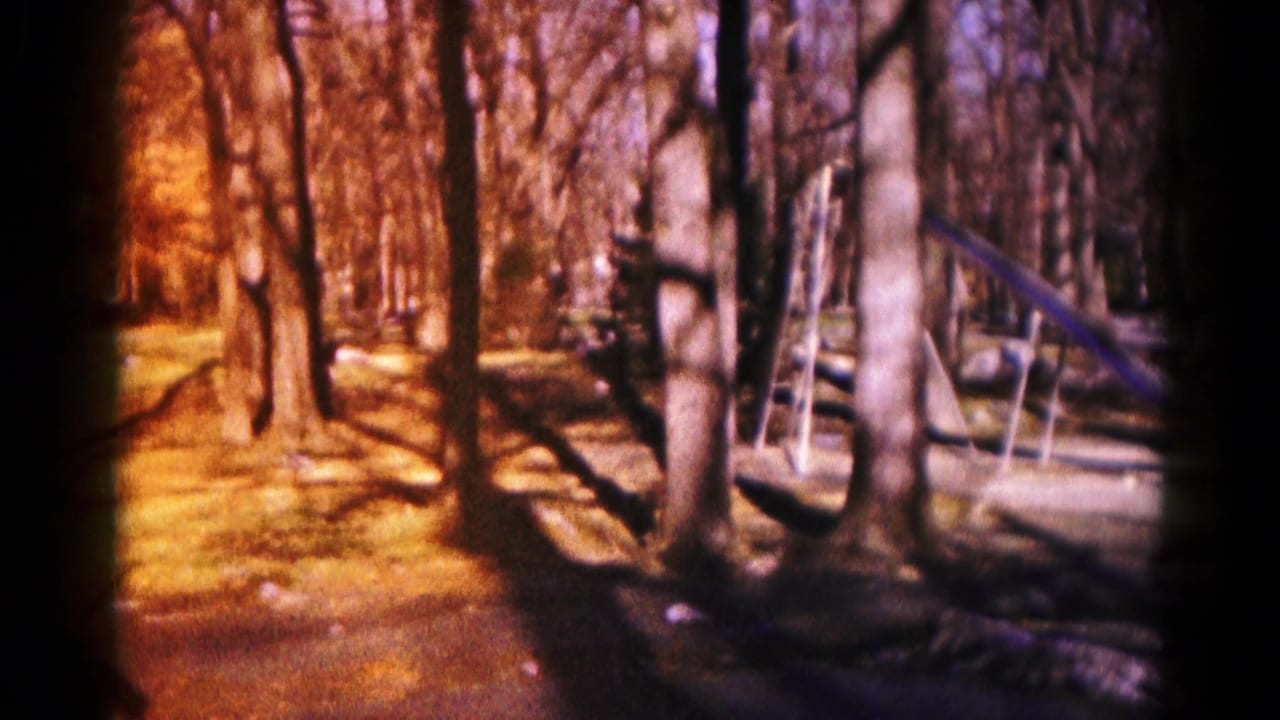 1959 Hagerstown 8mm frame showing a quiet wooded clearing with bare trees and a partially obscured playground slide.