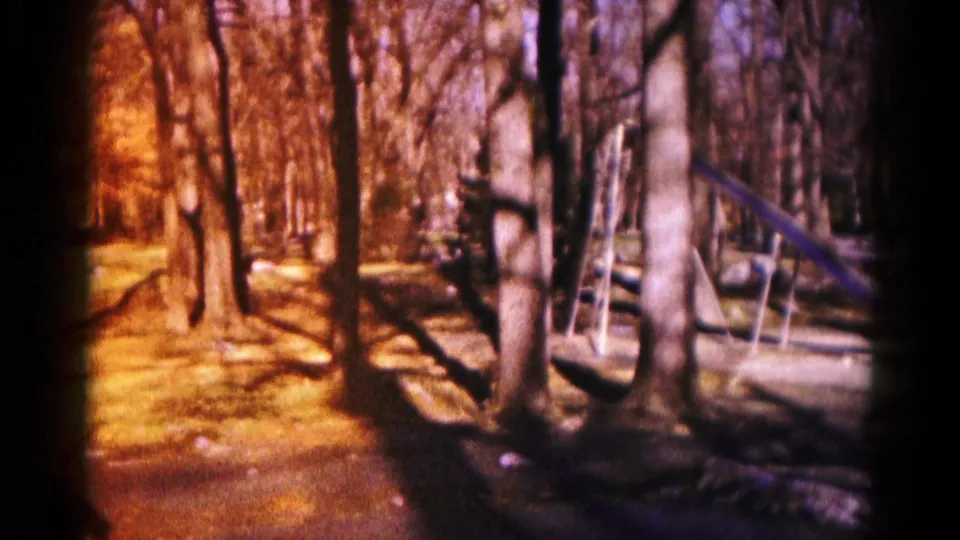 1959 Hagerstown 8mm frame showing a quiet wooded clearing with bare trees and a partially obscured playground slide.