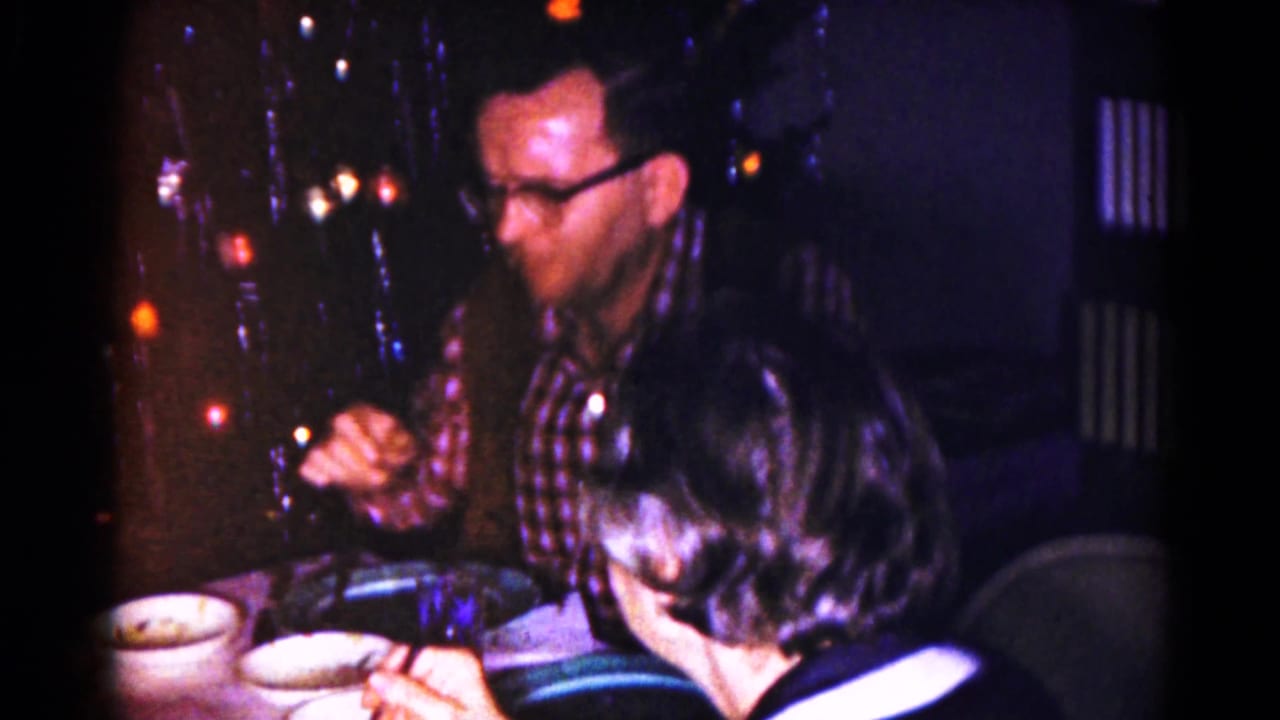 A man in a plaid shirt and glasses sits with a woman at a dining table near Christmas lights in the Hagerstown home interior.