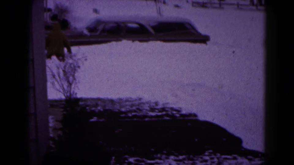 1959 Hagerstown frame showing a car buried along the snowy roadside, with a bundled person partly visible at the edge of the frame.