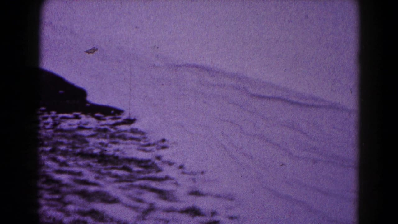 Purple-tinted 8mm frame showing snowdrifts and dark film borders.