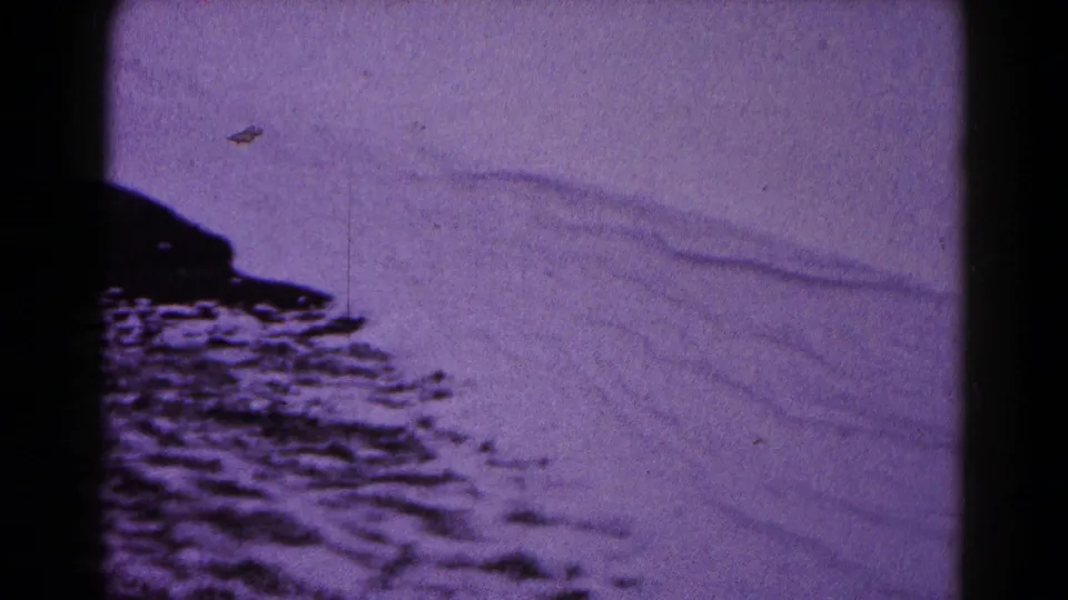 1959 Hagerstown 8mm home-movie frame with snow-covered ground, soft drift lines, and heavy dark scan borders.