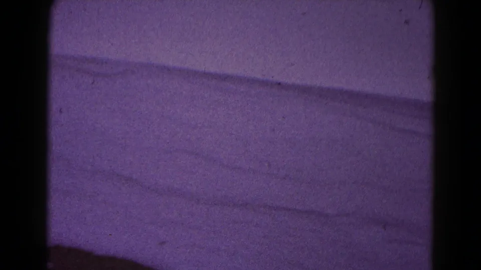 Soft purple-tinted 8mm frame of snowy terrain or an open winter slope, likely from the Hagerstown home-movie clip.