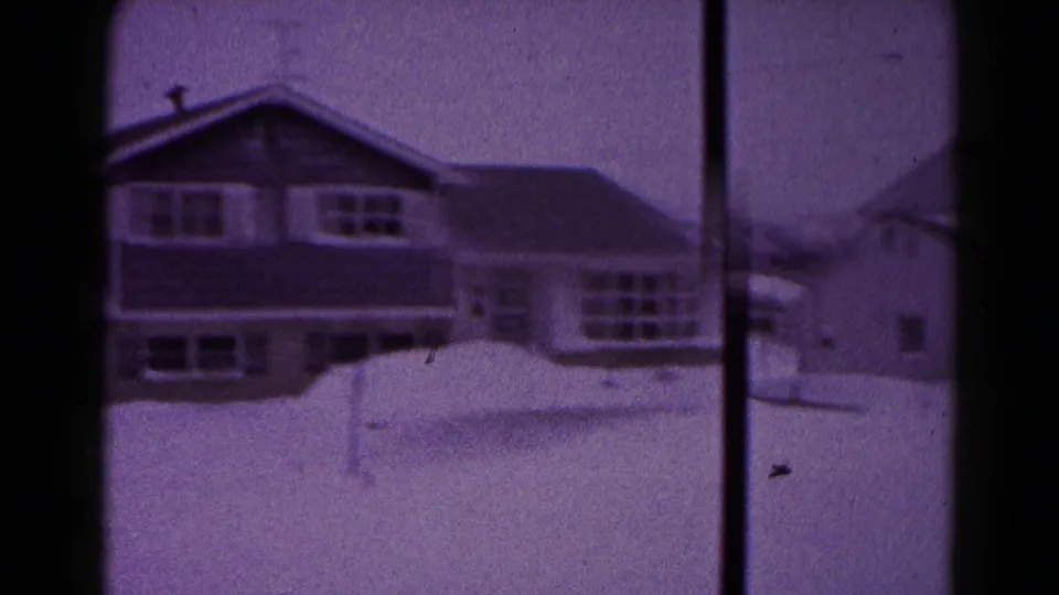 1959 Hagerstown frame of a two-story house with snowbanks, soft focus, and visible 8mm frame edges.