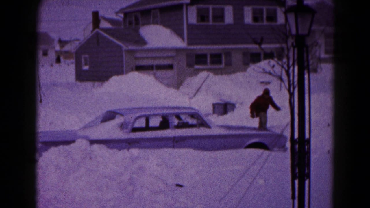 In Hagerstown, Maryland, 1959, a man approaches a snow-buried four-door sedan on a residential street.