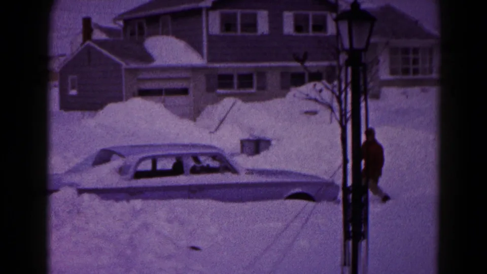 A buried sedan remains in the foreground as the man moves near a lamppost in snowy Hagerstown, Maryland.