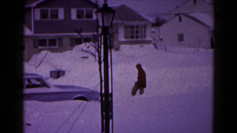 The man walks through deep snow near the partly framed sedan in the 1959 Hagerstown home-movie scene.