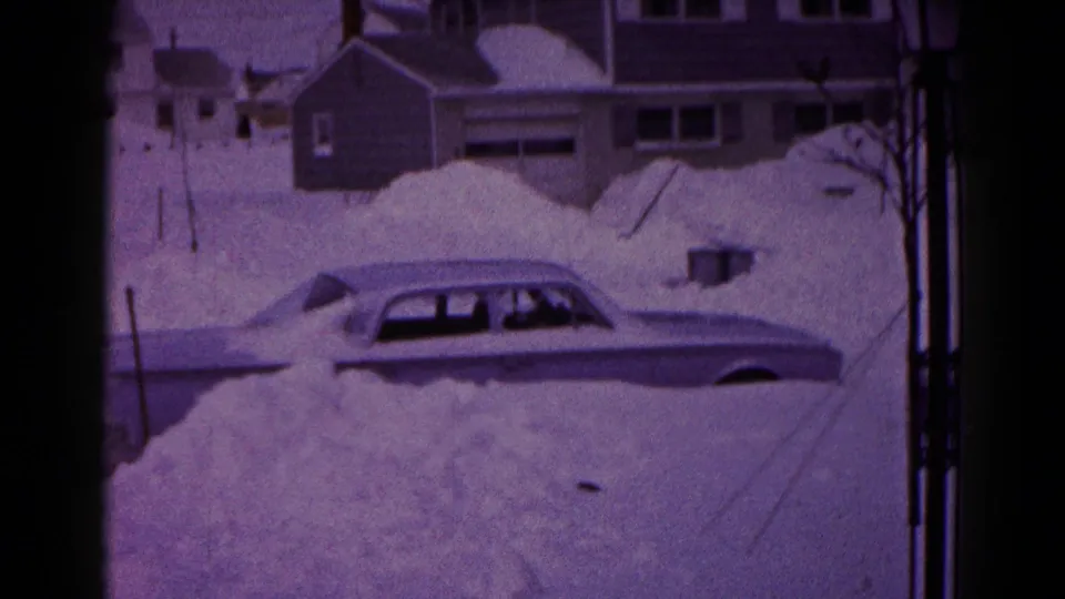 The sedan remains partly visible above heavy snow in a Hagerstown residential area, with houses and garages behind it.