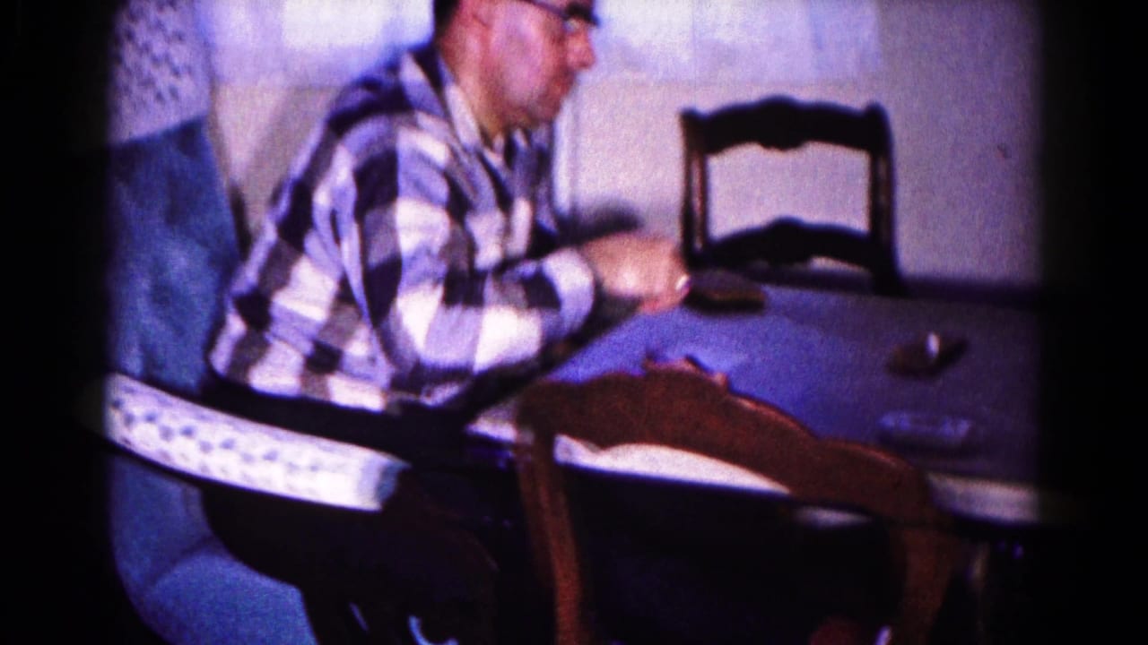 In 1959 Hagerstown home-movie footage, a man in glasses and a checkered shirt sits at a table during a card game.
