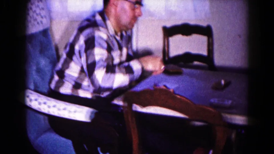 In 1959 Hagerstown home-movie footage, a man in glasses and a checkered shirt sits at a table during a card game.