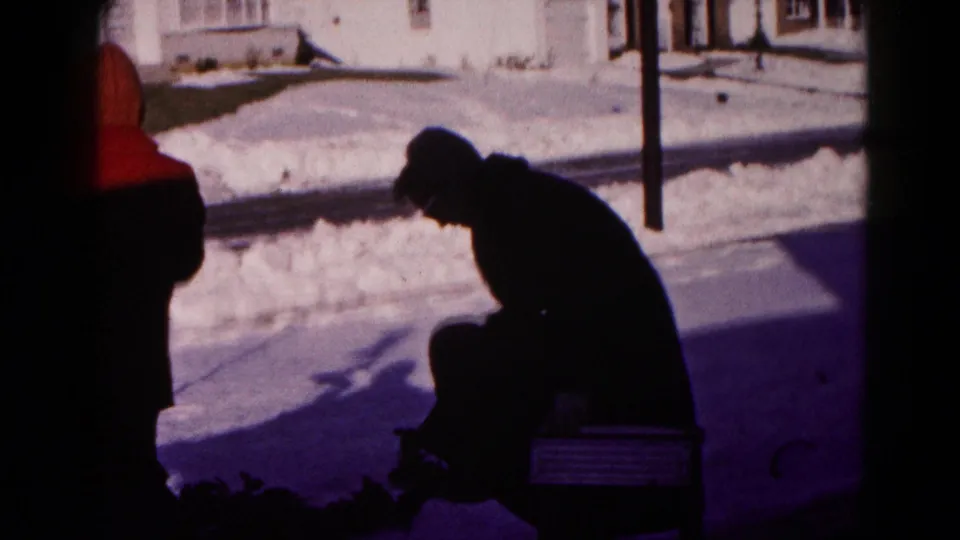 In the final frame, the man sits on the small bench in the snowy Hagerstown yard, still bent forward near the bright sidewalk and house exterior.