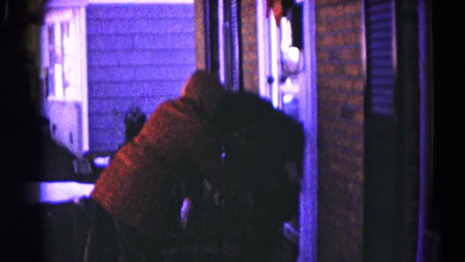1959 Hagerstown home-movie frame with a person in a red sweater bending near a doorway before the Christmas tree view.