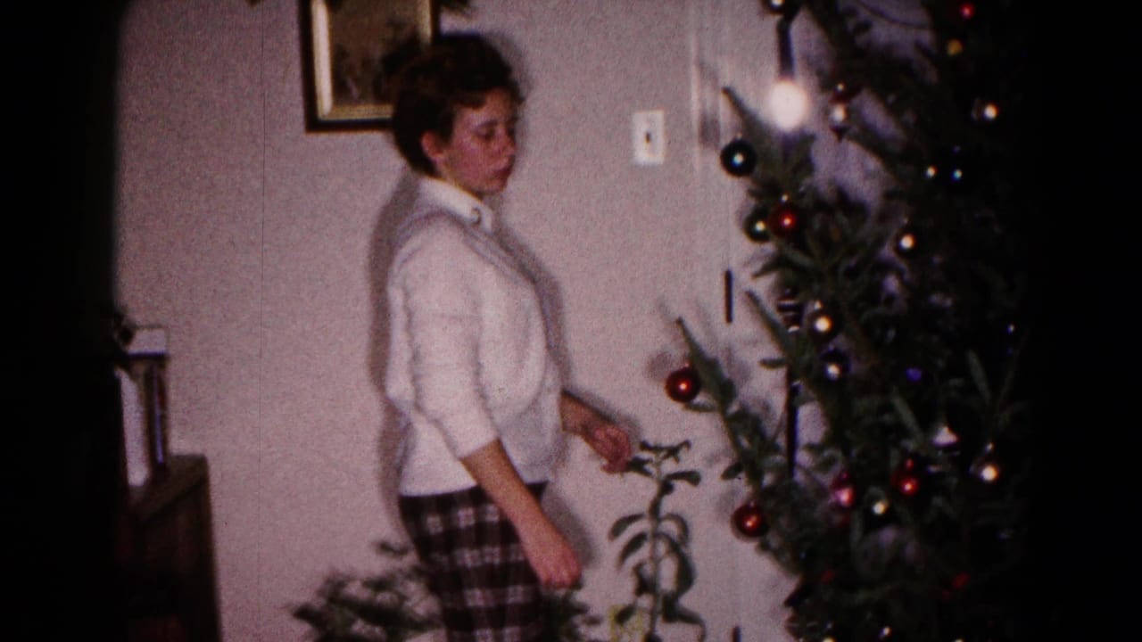 Young woman stands beside a decorated Christmas tree in a living room.