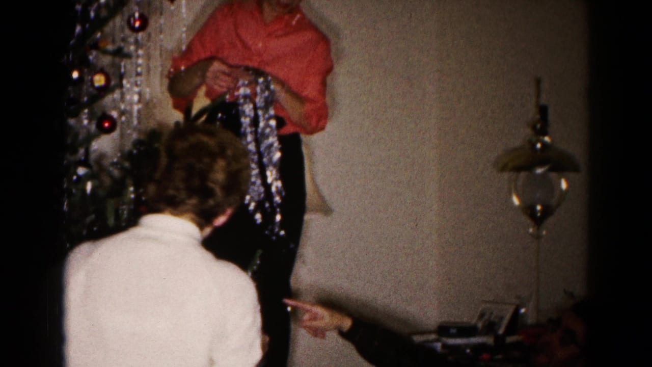 1959 Hagerstown frame of adults finishing tinsel decoration on an indoor Christmas tree in a private home.