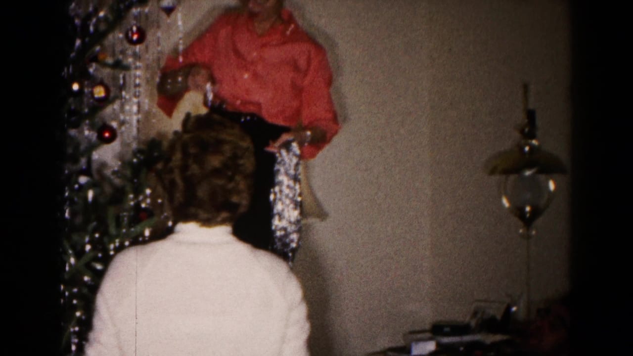 1959 Hagerstown home-movie frame of a woman adding tinsel to a Christmas tree while another watches from below.