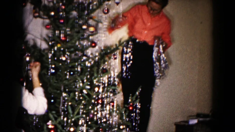 1959 Hagerstown indoor Christmas scene with a woman beside a tinsel-covered tree and another person partly visible at left.