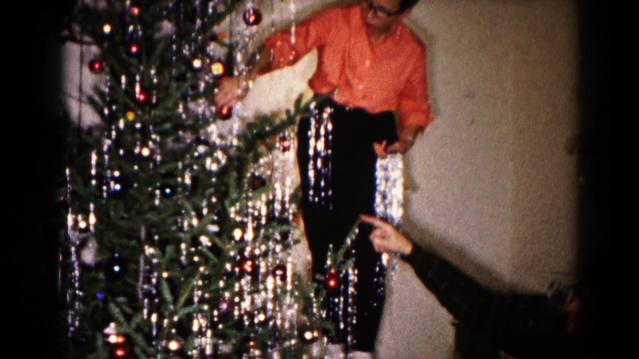 The final frame shows the man reaching toward the ornamented Christmas tree while tinsel hangs and another person points from the edge of the shot.