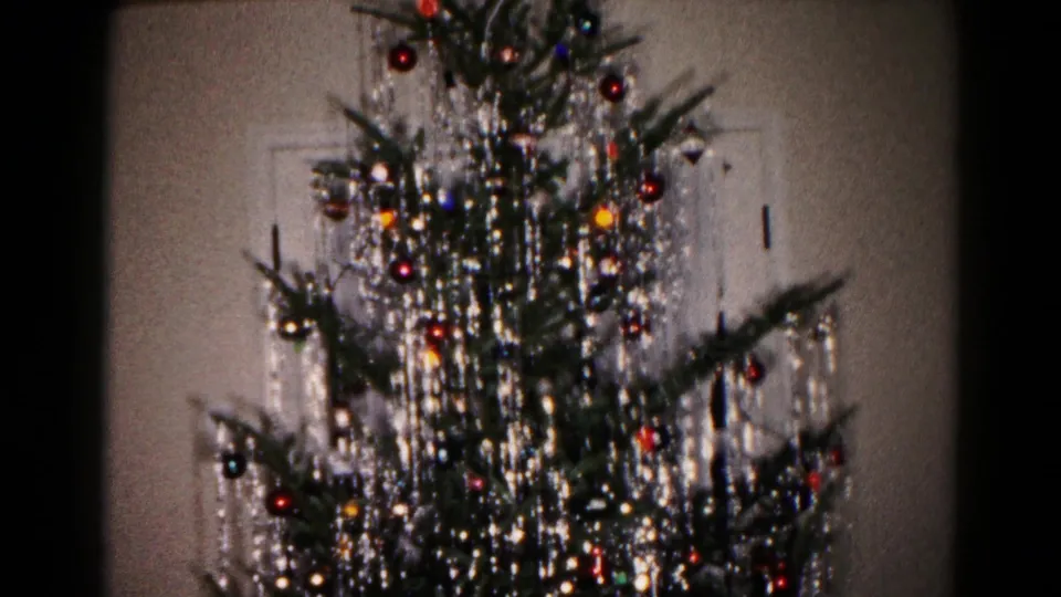 A final 1959 Hagerstown home-movie frame shows the decorated Christmas tree with dense silver tinsel and colored ornaments against an interior wall.