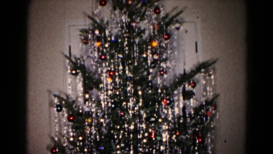 1959 Hagerstown home-movie frame showing a decorated Christmas tree with silver tinsel, colored ornaments and small lights indoors.