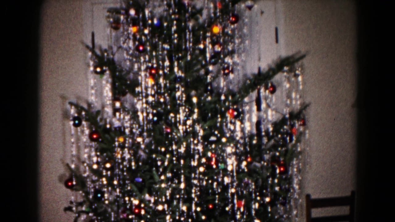 Decorated Christmas tree with tinsel and ornaments, with a wooden chair at the right edge.