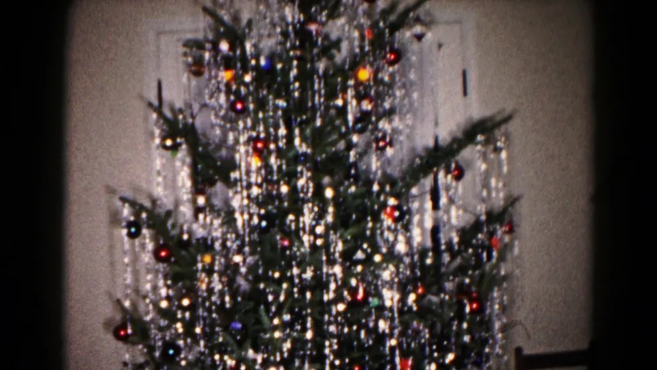 1959 Hagerstown home-movie frame showing the camera pan moving up the decorated Christmas tree toward the upper branches.