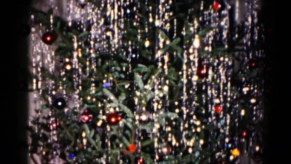 Hagerstown 1959 home-movie still of a Christmas tree close-up, showing shimmering tinsel, colored ornaments, and soft 8mm exposure.