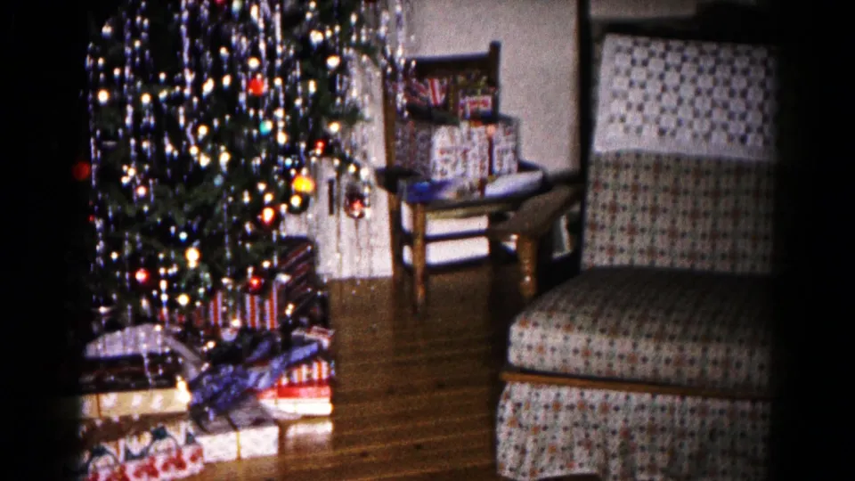 1959 Hagerstown home-movie view of a Christmas tree, presents, side table, and upholstered chair in a private room.