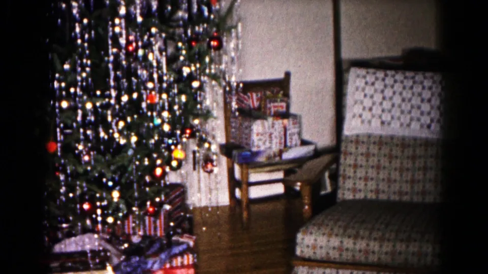 1959 Hagerstown frame showing a tinsel-covered Christmas tree, stacked gifts, side table, and patterned chair.