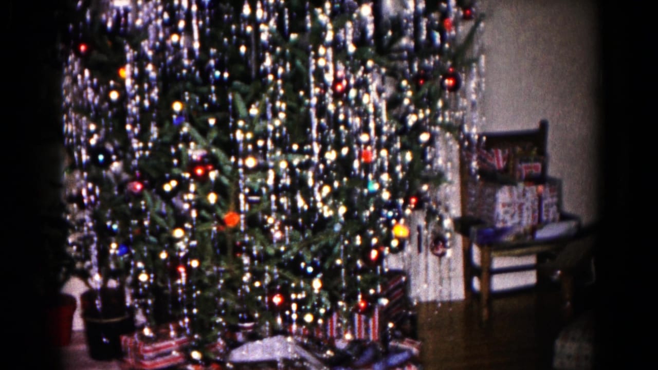 1959 Hagerstown frame with a decorated Christmas tree, dense silver tinsel, colored ornaments, wrapped presents, and a chair at right.