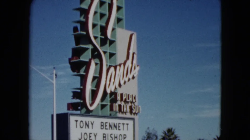 1959 Nevada home-movie frame showing the Sands sign with marquee lettering beneath it against a clear sky.