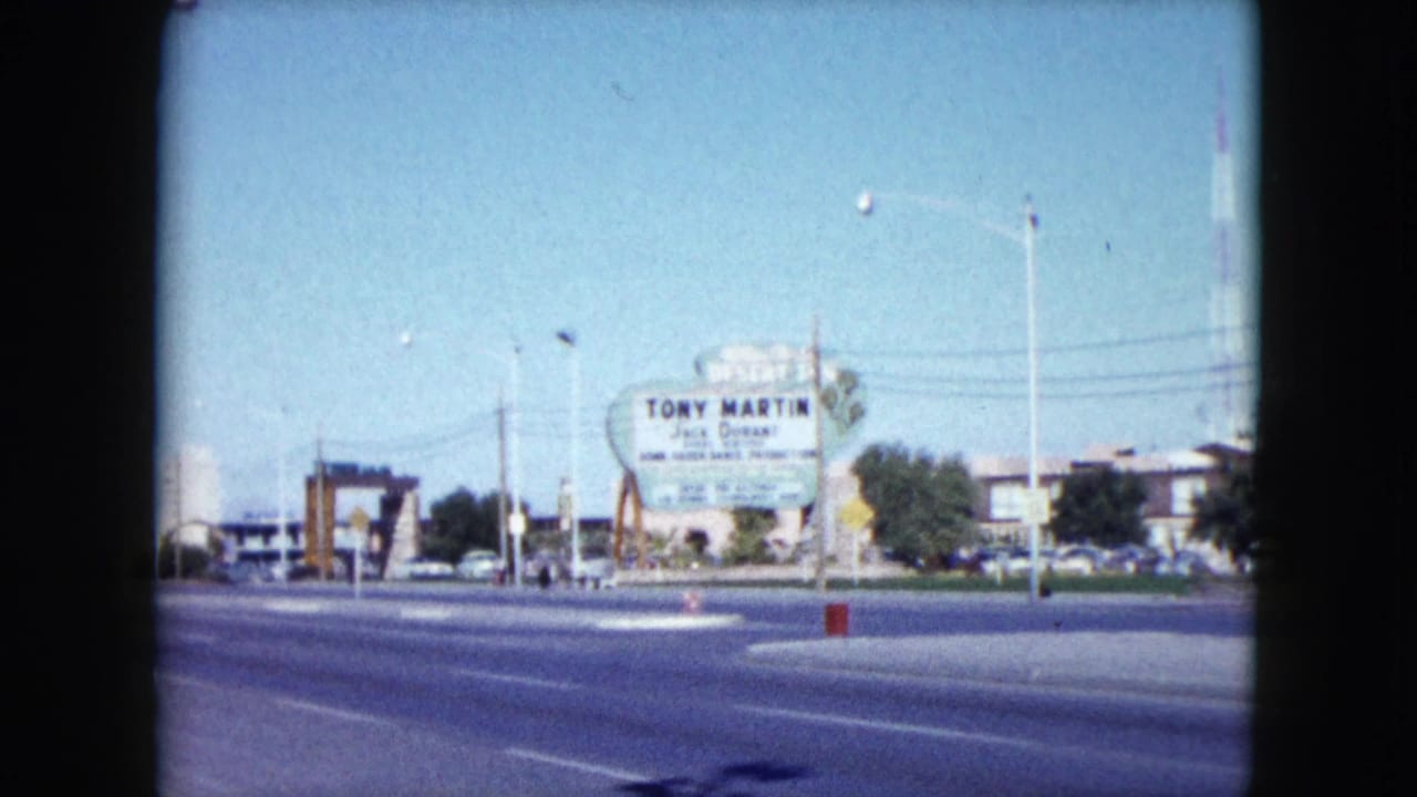 Wide roadside view with a Tony Martin and Jack Durant sign, street lanes, poles, and distant buildings.