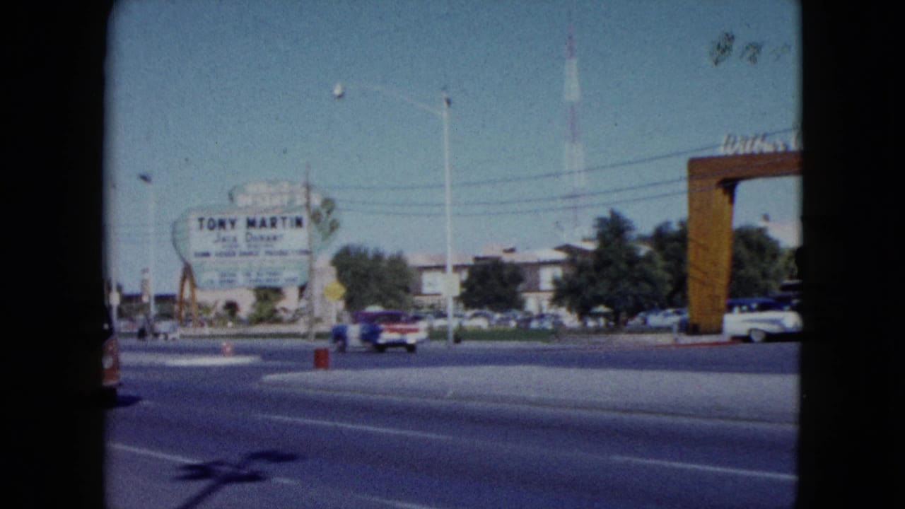1959 Nevada roadside view showing the Tony Martin and Jack Durant sign, passing classic cars, utility poles, trees, and a wooden archway on the right.
