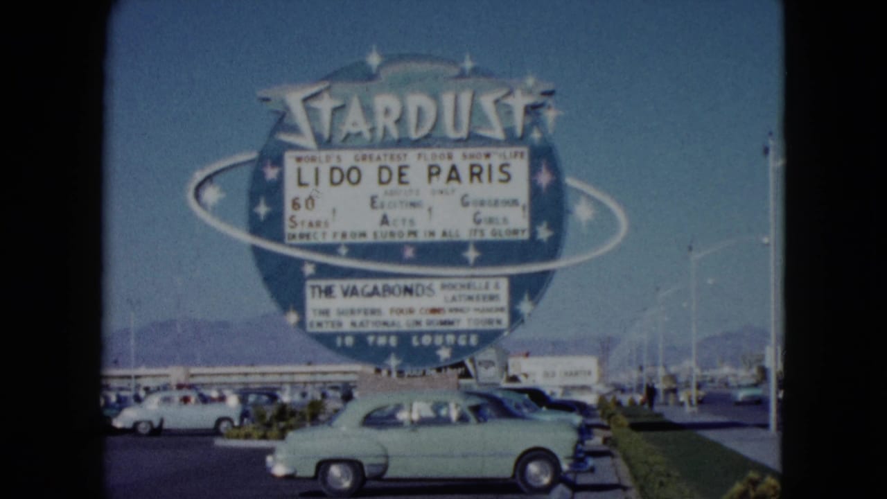 Large Stardust sign with a light green sedan passing in front.