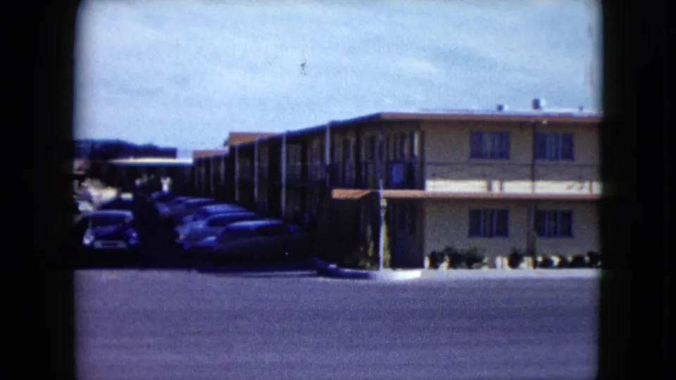 The final frame shows the building from an angle, with several parked cars in shadow along the side and the open lot in front.