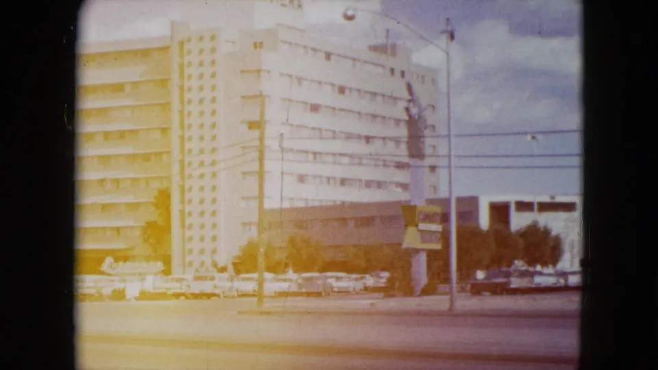 Bright 8mm frame showing the Riviera hotel exterior, roadway, cars, and visible signage in Nevada.