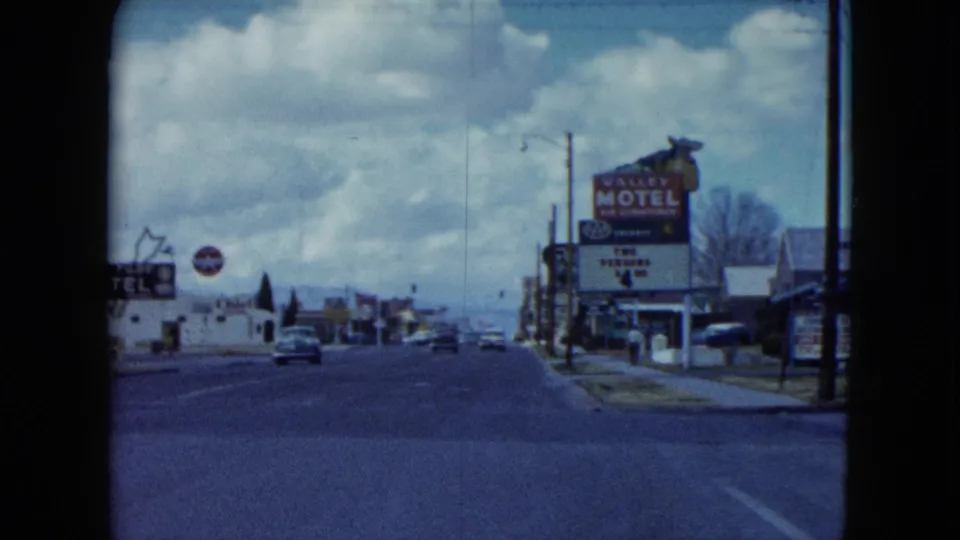 Moving-car view of a Nevada street with the Valley Motel sign prominent beside the road.