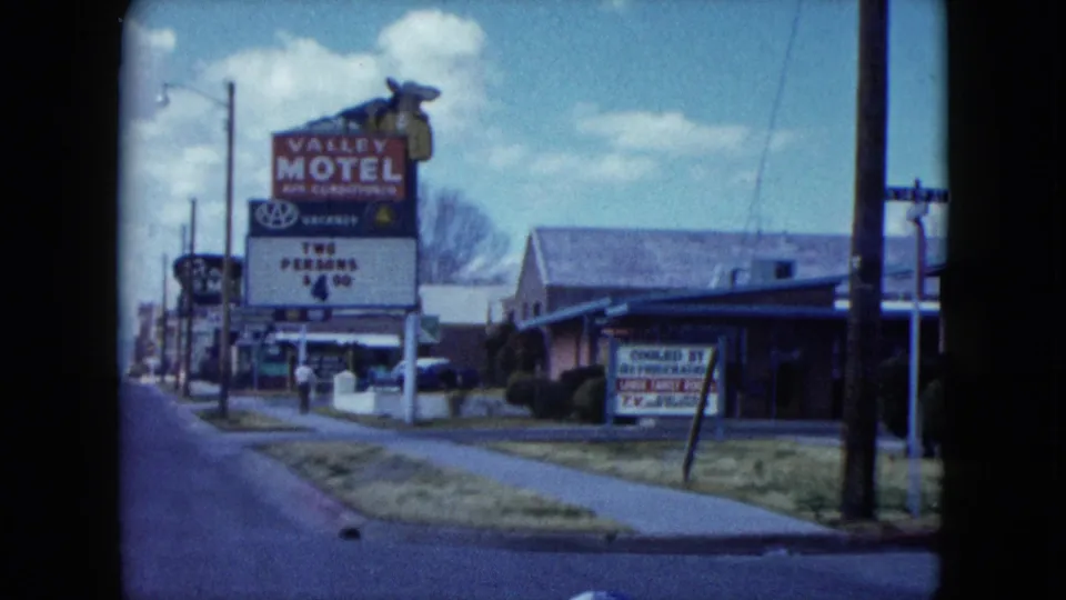 End-frame view of the Valley Motel sign and roadside buildings in a 1959 Nevada town.