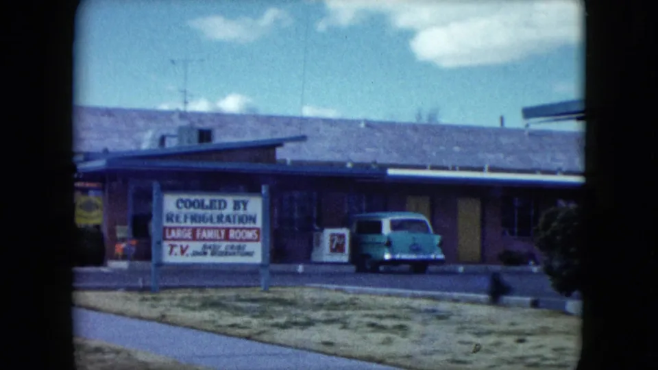 1959 Nevada motel frontage with a marquee advertising cooled rooms and a light green station wagon parked outside.