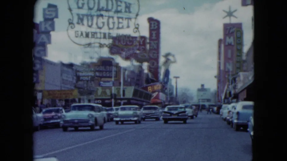 Forward-moving 1959 Nevada street view with classic cars, Golden Nugget signage, bingo signs, and commercial facades.
