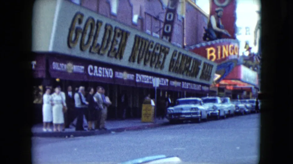 1959 Nevada casino street scene with pedestrians outside the Golden Nugget and vintage cars parked down the block.