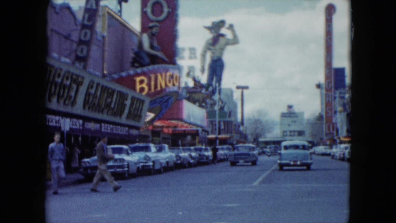Nevada street with vintage cars, pedestrians, casino signage, and a large cowboy statue above a bingo sign.