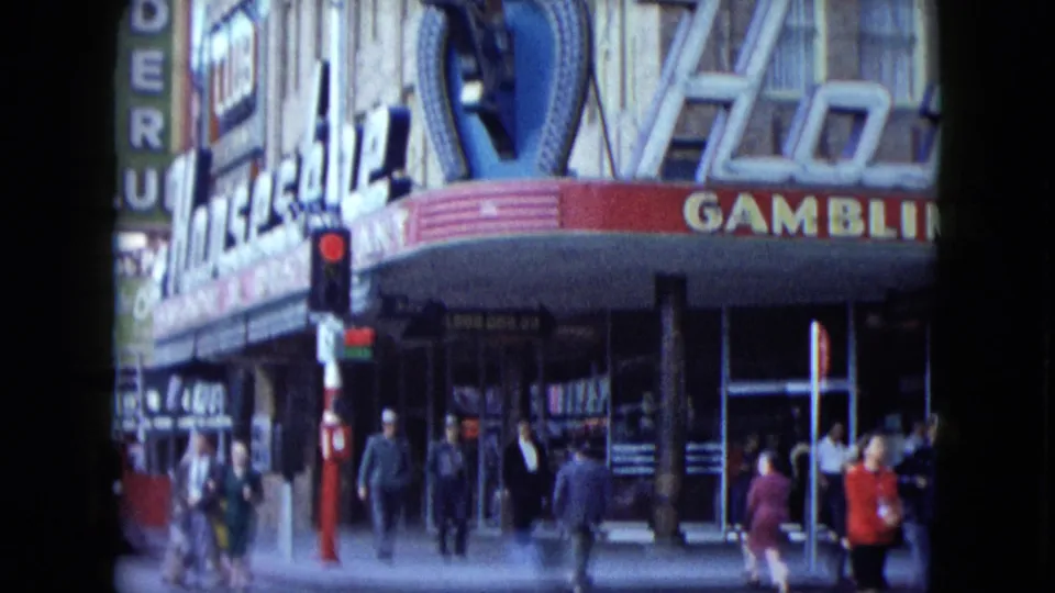 1959 Nevada casino block with people on the sidewalk, a red signal, and marquee-style signage.